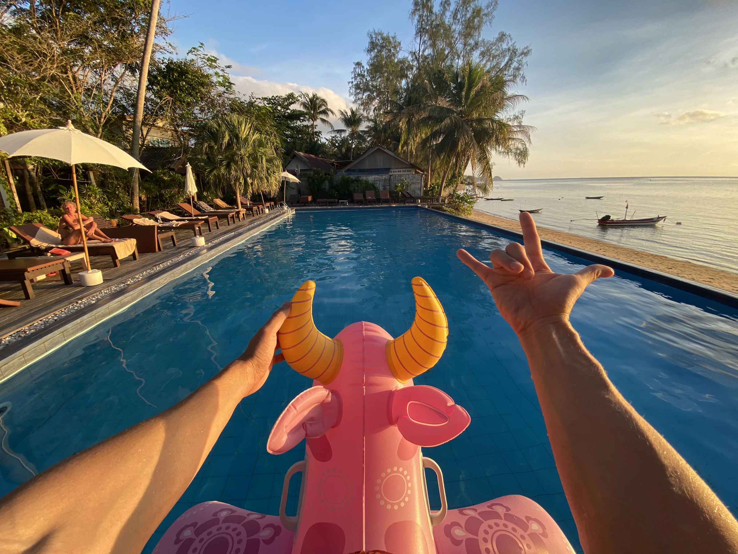 Person relaxing on a bright inflatable float in a tropical swimming pool