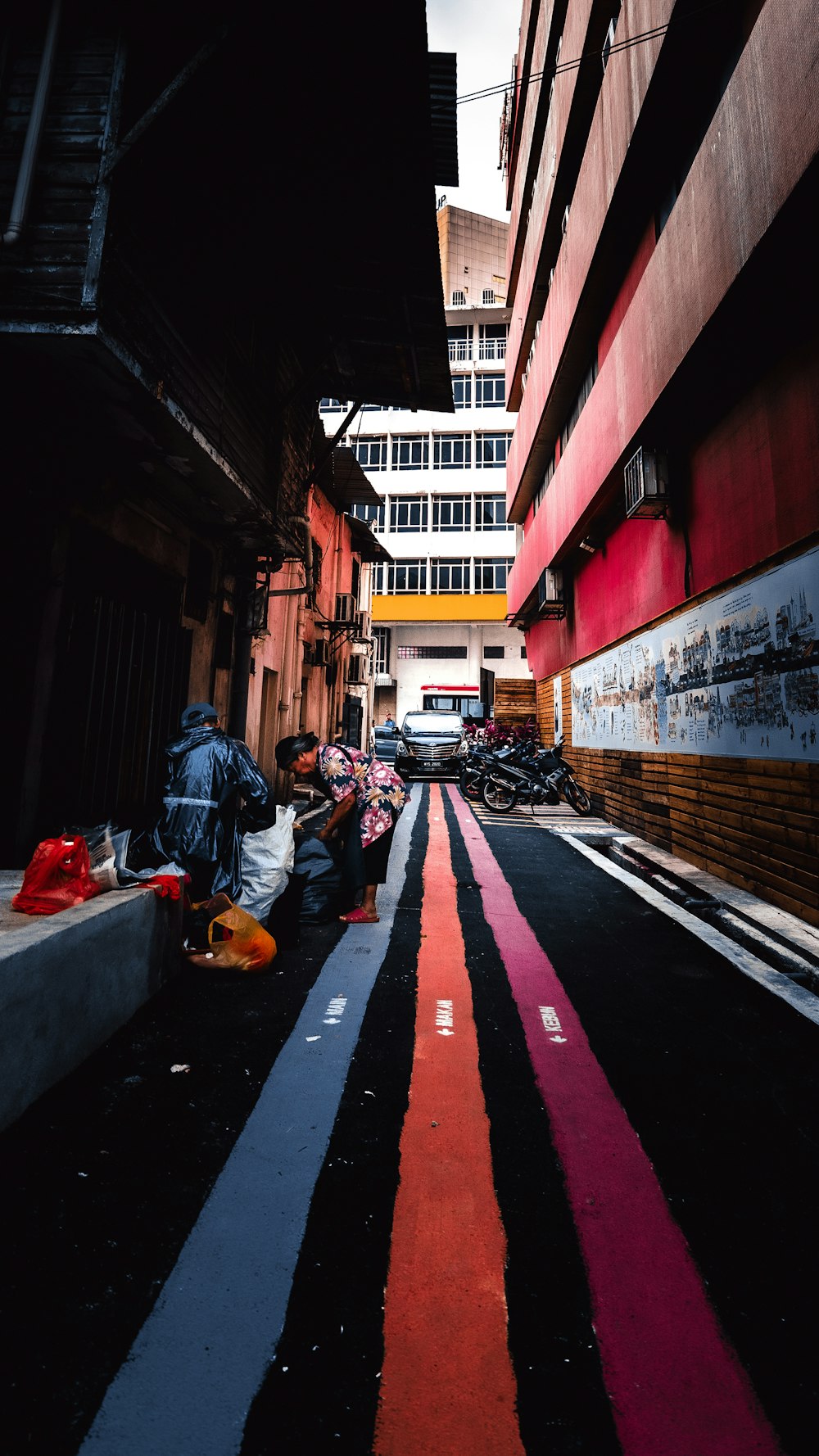 man in orange jacket sitting on sidewalk during daytime