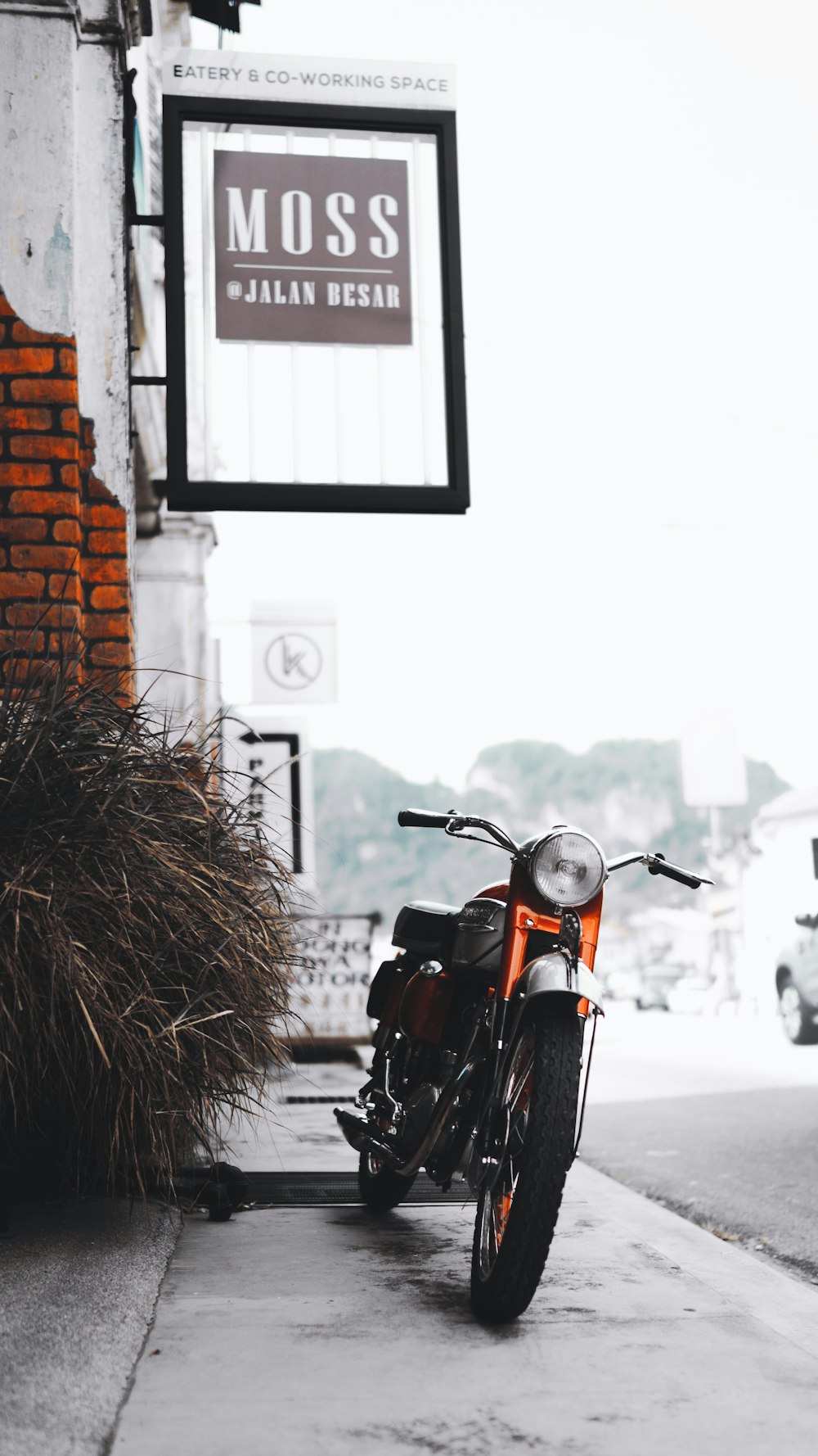 red and black motorcycle parked beside brown brick wall during daytime