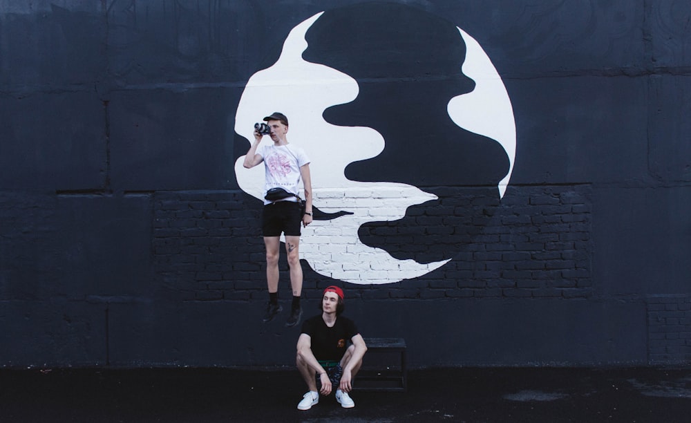 woman in white t-shirt and black shorts standing beside wall with graffiti