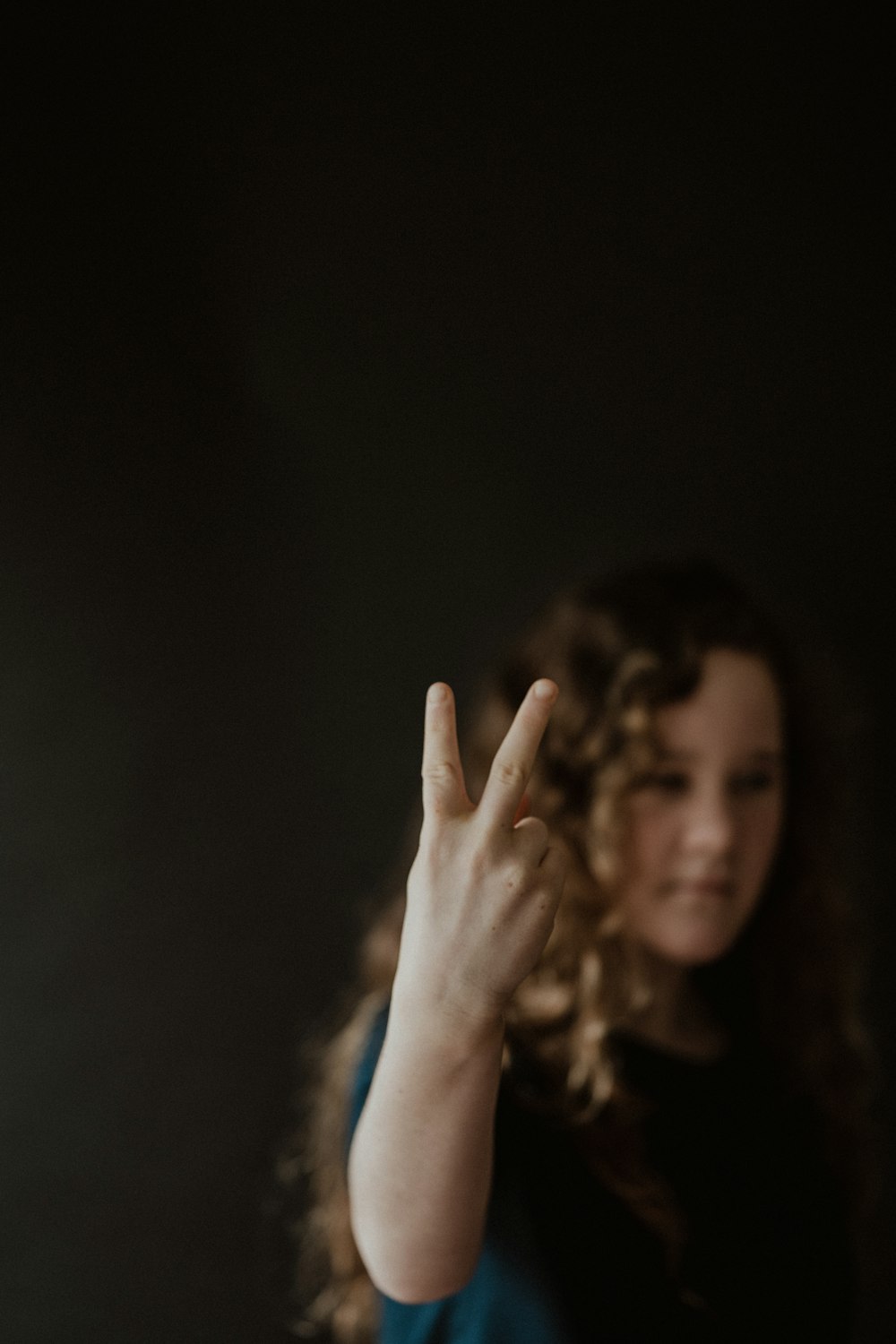 woman in blue shirt raising her hand