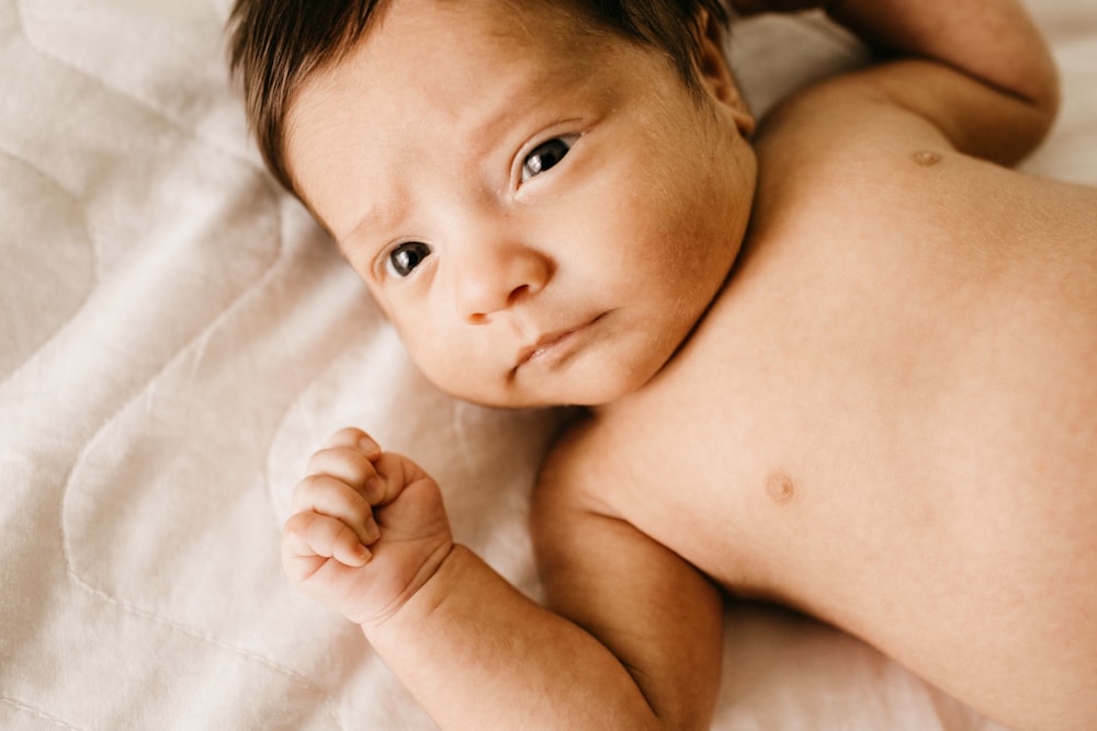 topless baby lying on bed