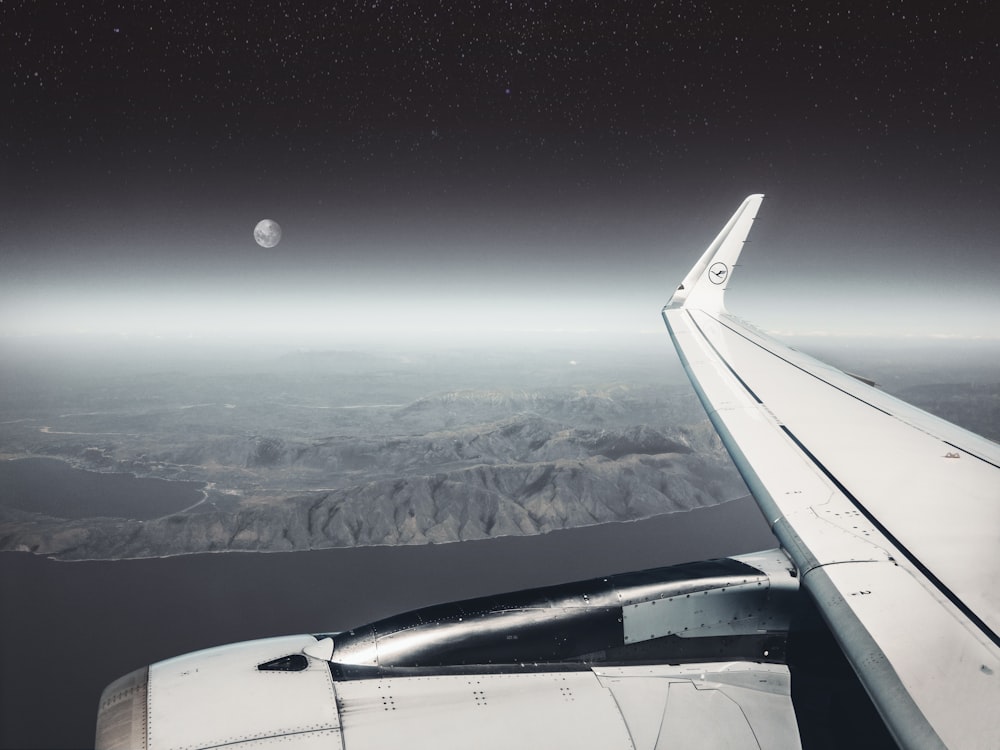 white airplane wing over the clouds during night time