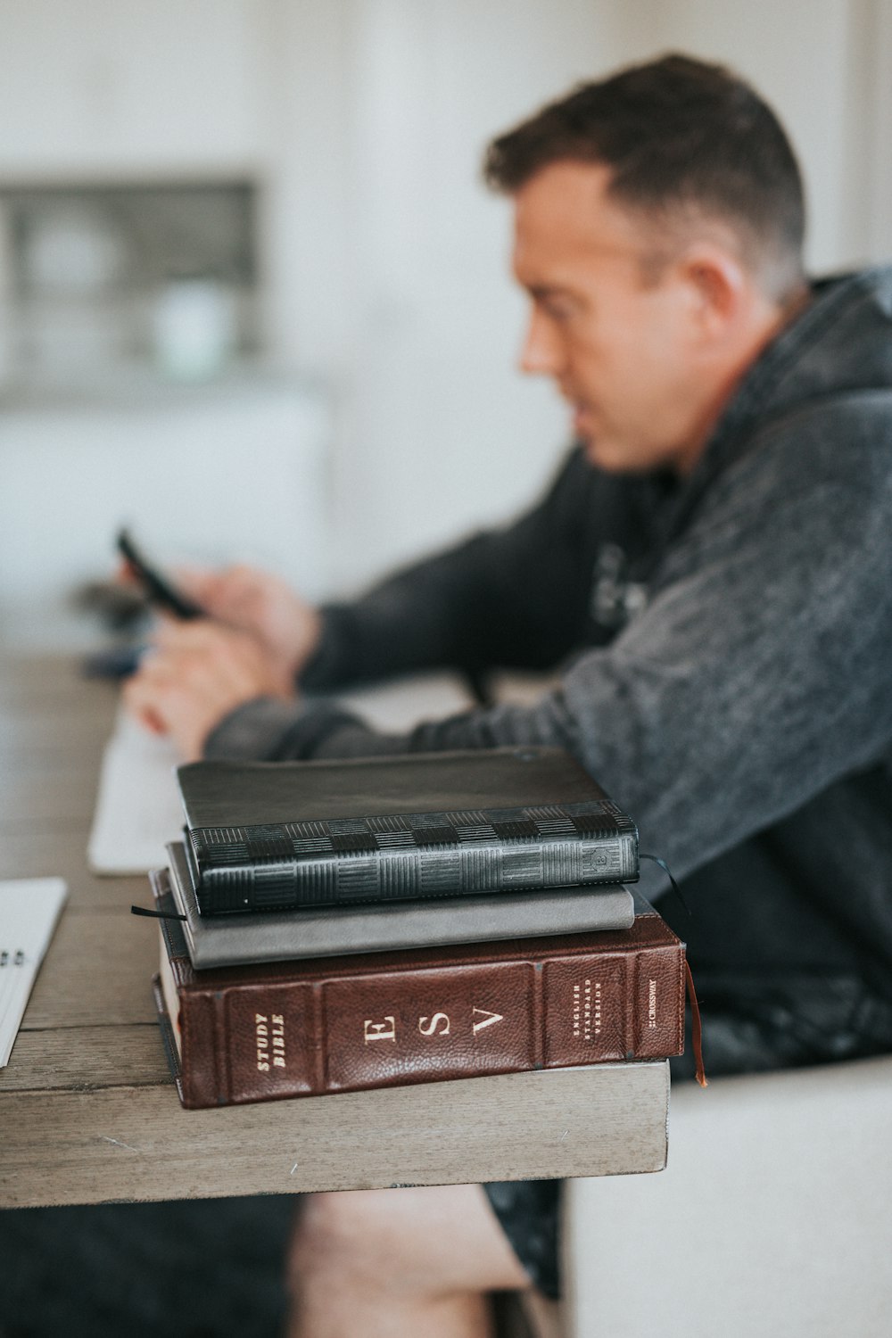 man in gray long sleeve shirt holding black smartphone