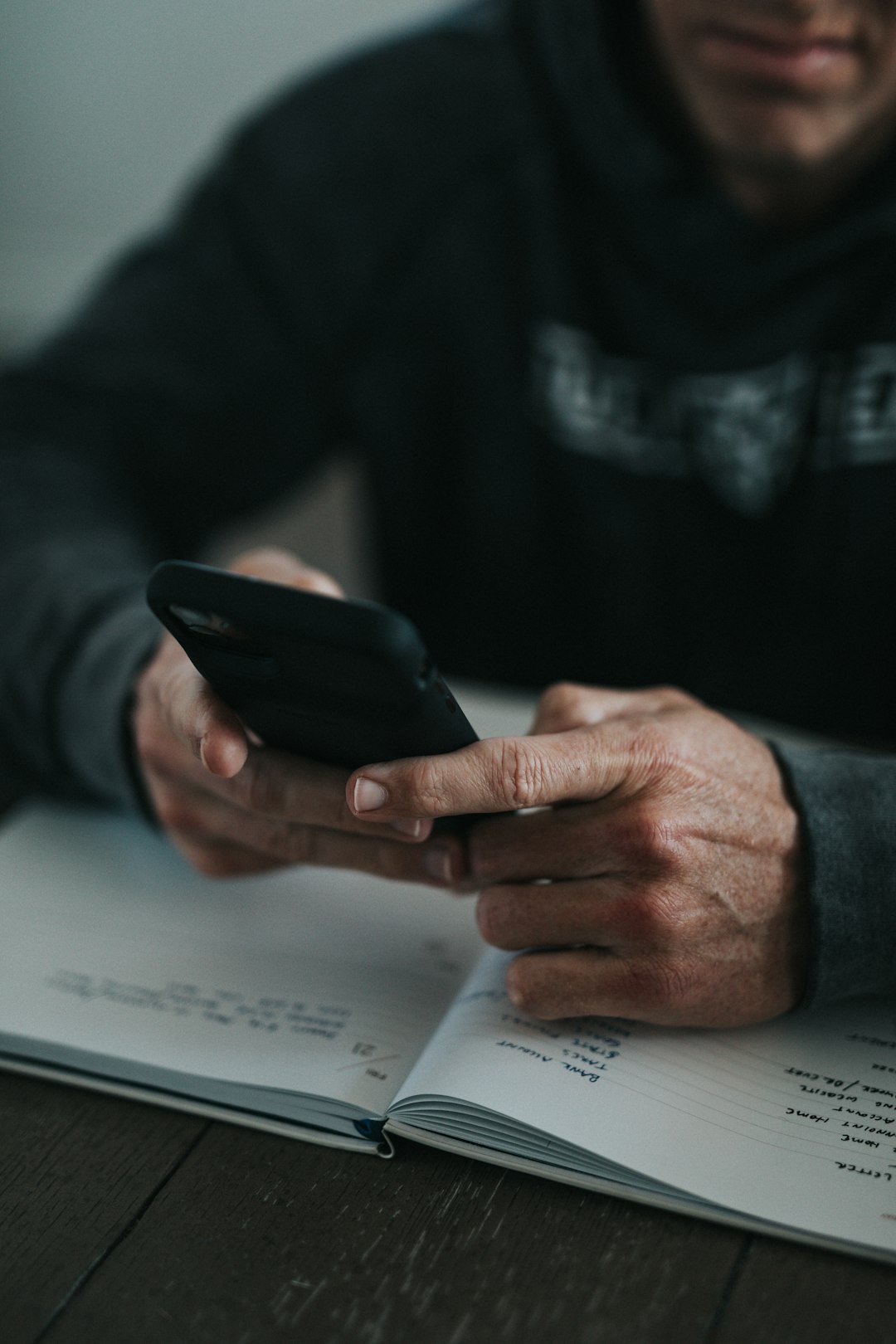 person holding black smartphone on white paper