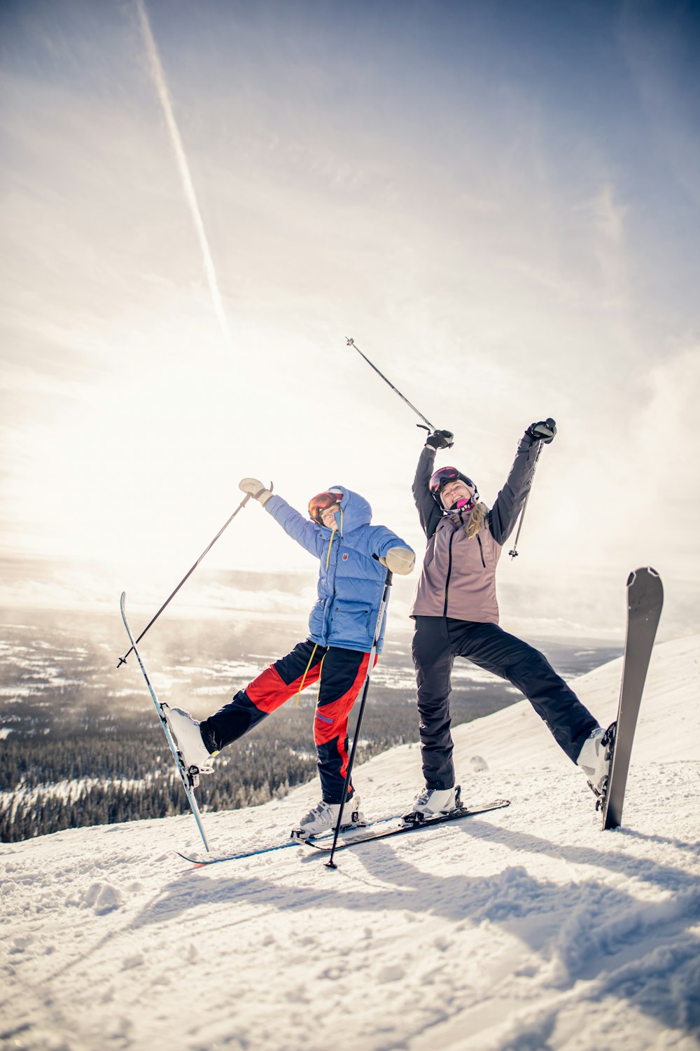 2 personas con pantalones blancos y hojas de esquí de nieve negras de pie en el suelo cubierto de nieve durante