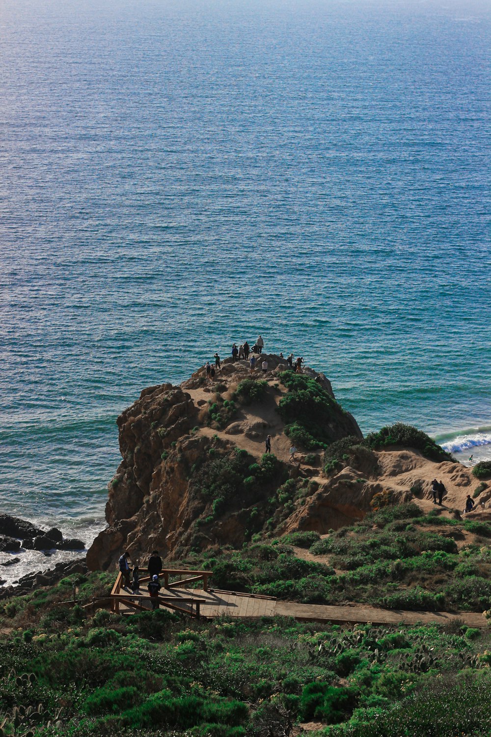 people standing on rock formation near sea during daytime