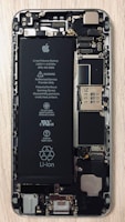 An open view of a smartphone revealing its internal components, including a prominent Li-ion battery and various microchips and circuits. The intricate hardware layout is visible with screws and connectors.