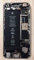 An open view of a smartphone revealing its internal components, including a prominent Li-ion battery and various microchips and circuits. The intricate hardware layout is visible with screws and connectors.
