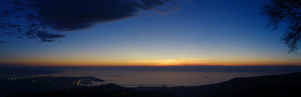 the sun is setting over a city and a body of water