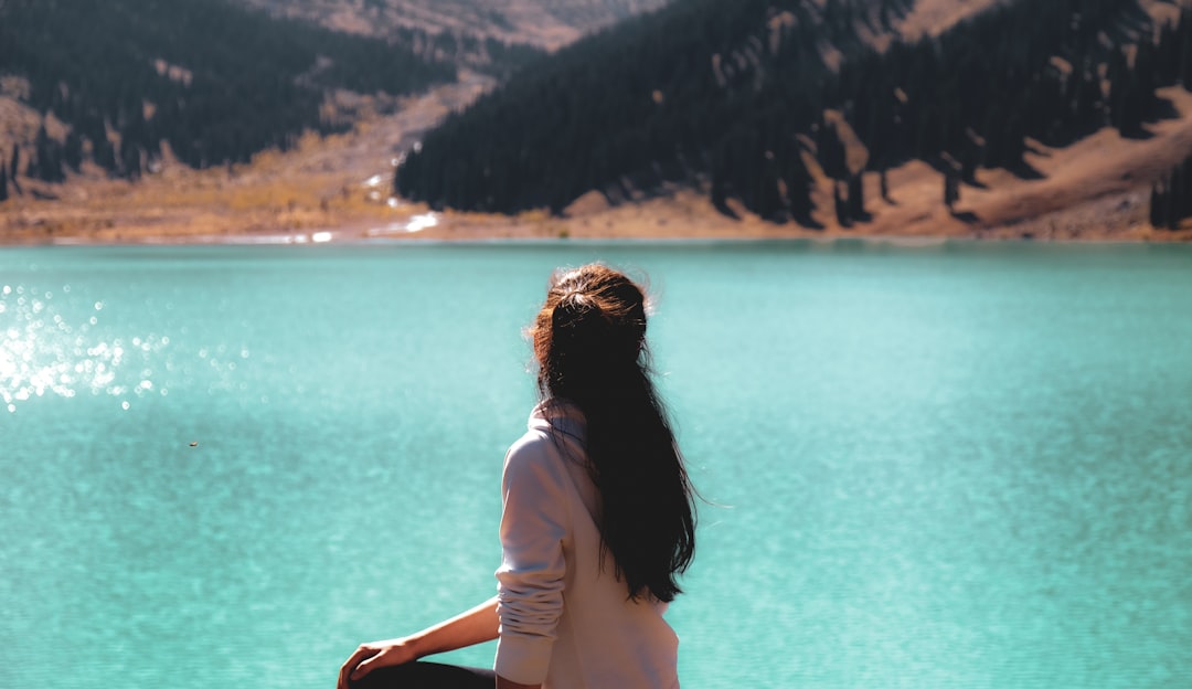 woman in white shirt standing near body of water during daytime in Almaty Region Kazakhstan