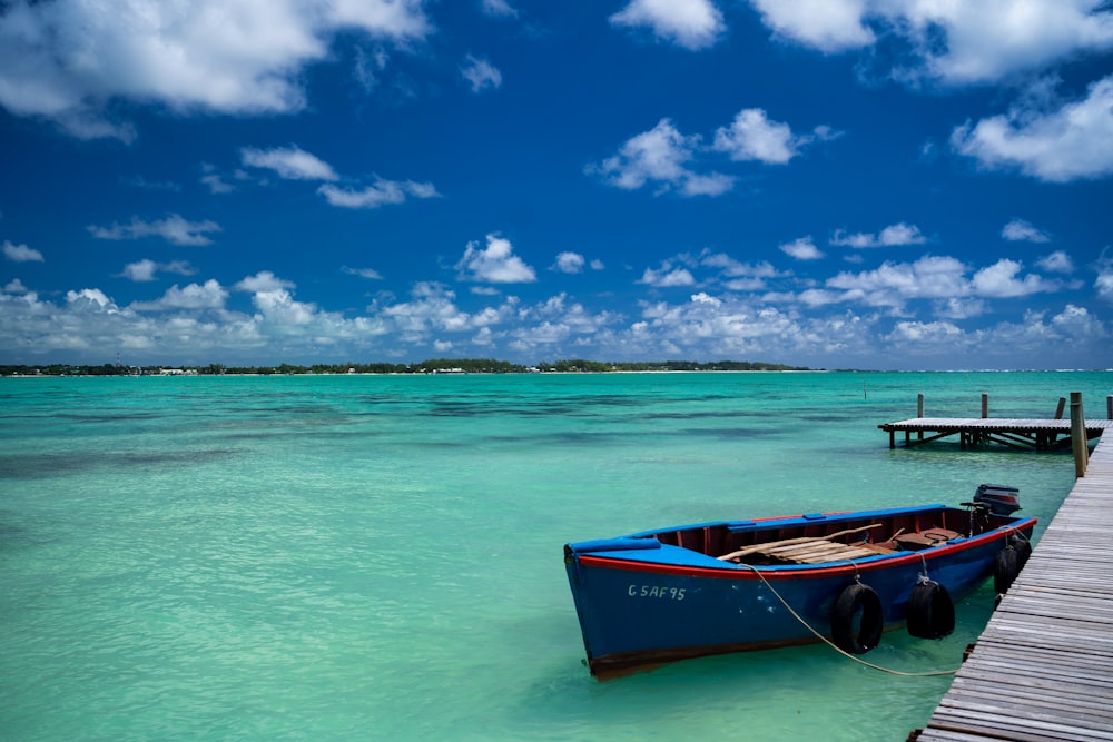 red and black boat on sea under blue sky during daytime