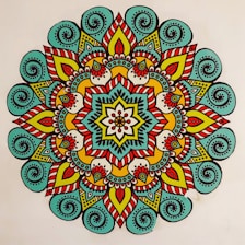 A vibrant, colorful mandala featuring intricate patterns and symmetrical designs. The mandala has a central flower-like motif surrounded by layers of geometric and floral shapes. The design is characterized by the use of bold lines and a variety of colors, creating a visually striking appearance.