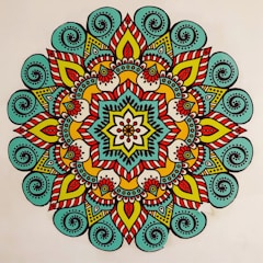 A vibrant, colorful mandala featuring intricate patterns and symmetrical designs. The mandala has a central flower-like motif surrounded by layers of geometric and floral shapes. The design is characterized by the use of bold lines and a variety of colors, creating a visually striking appearance.