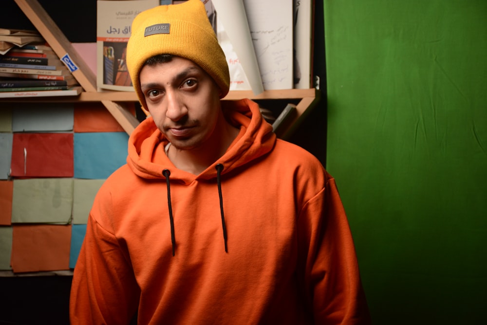 a man wearing an orange hoodie and a yellow hat