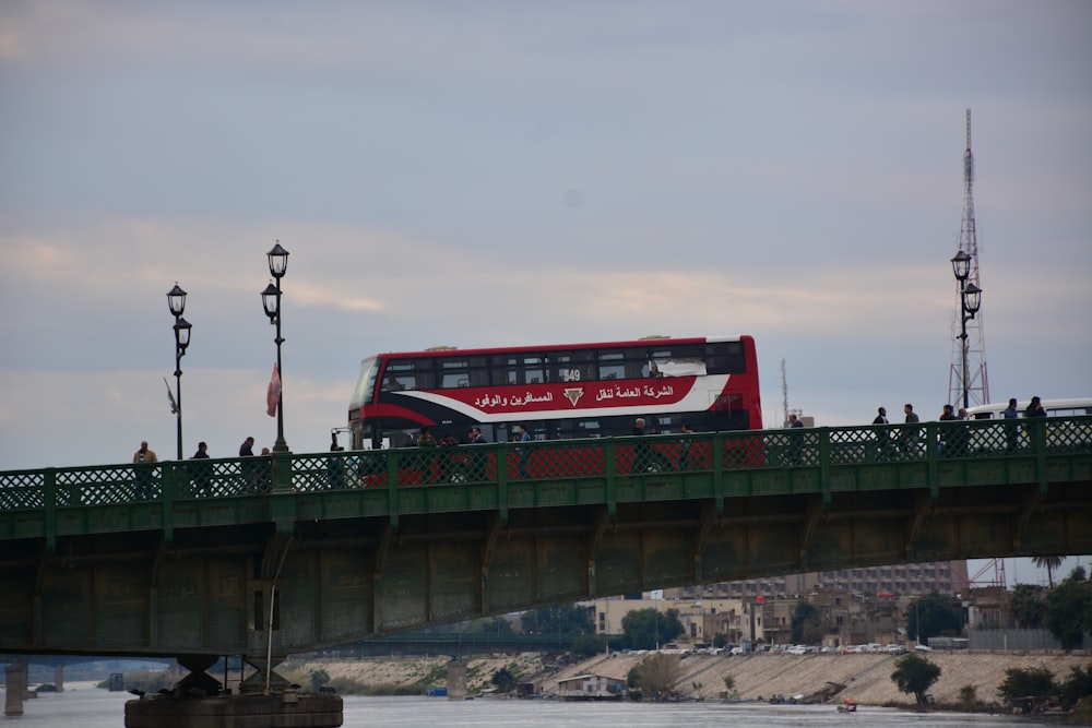 a red double decker bus driving over a bridge