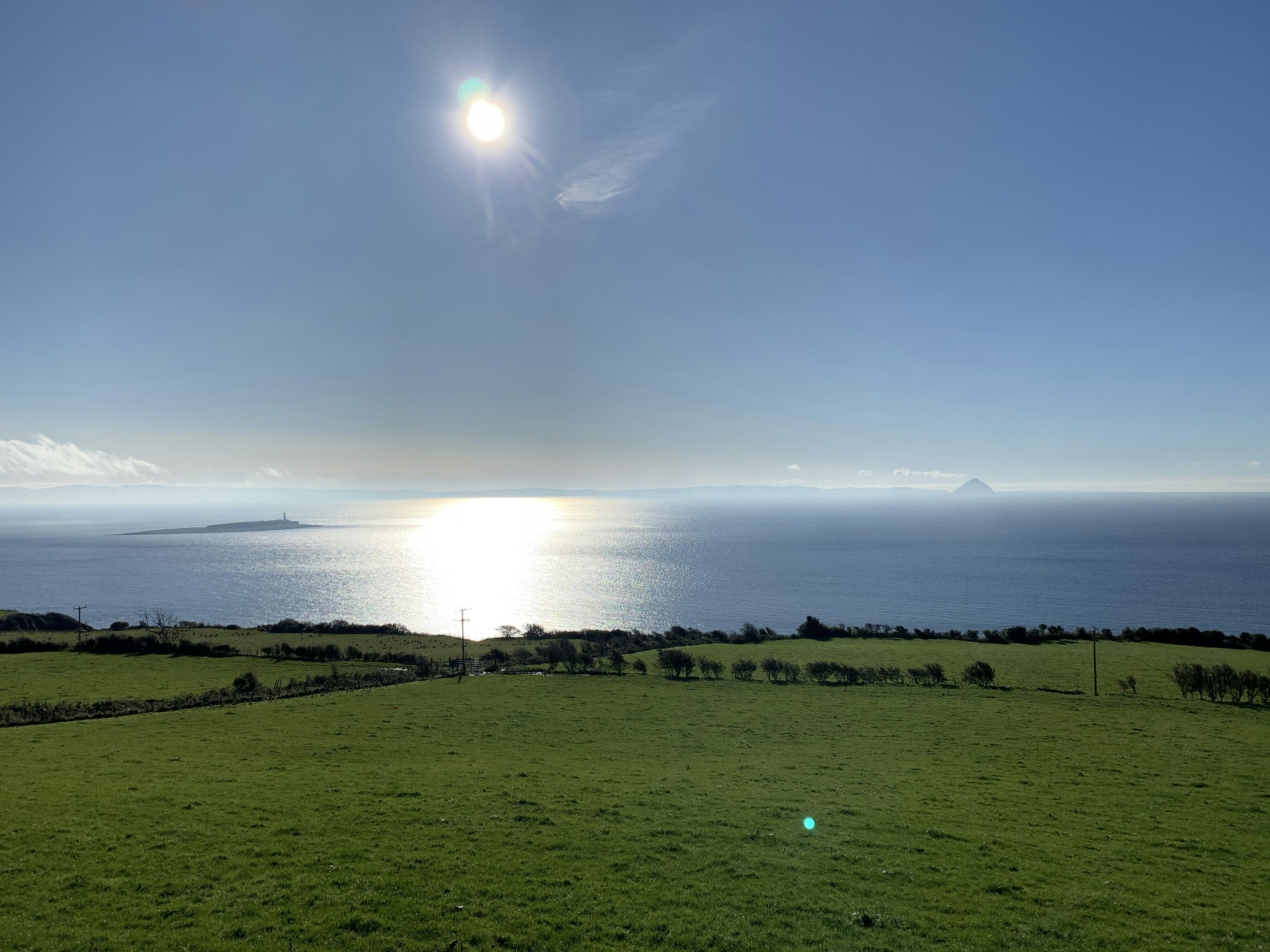 green grass field near body of water during daytime, Looking south-west towards Pladda and its lighthouse, Isle of Arran, UK