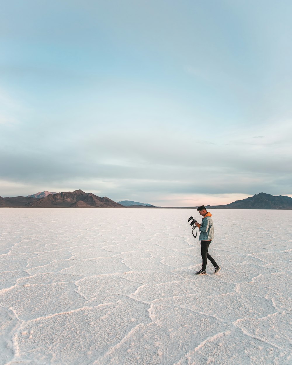 man in black jacket and black pants walking on white sand during daytime