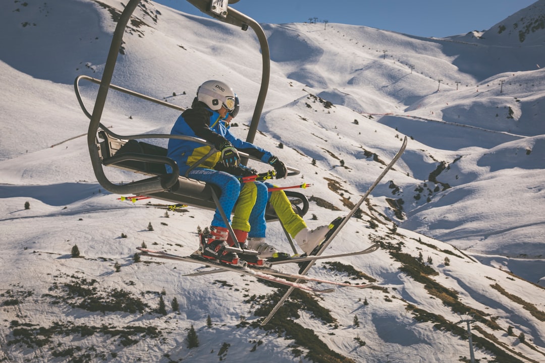 boy in blue jacket and red pants riding ski blades on snow covered mountain during daytime