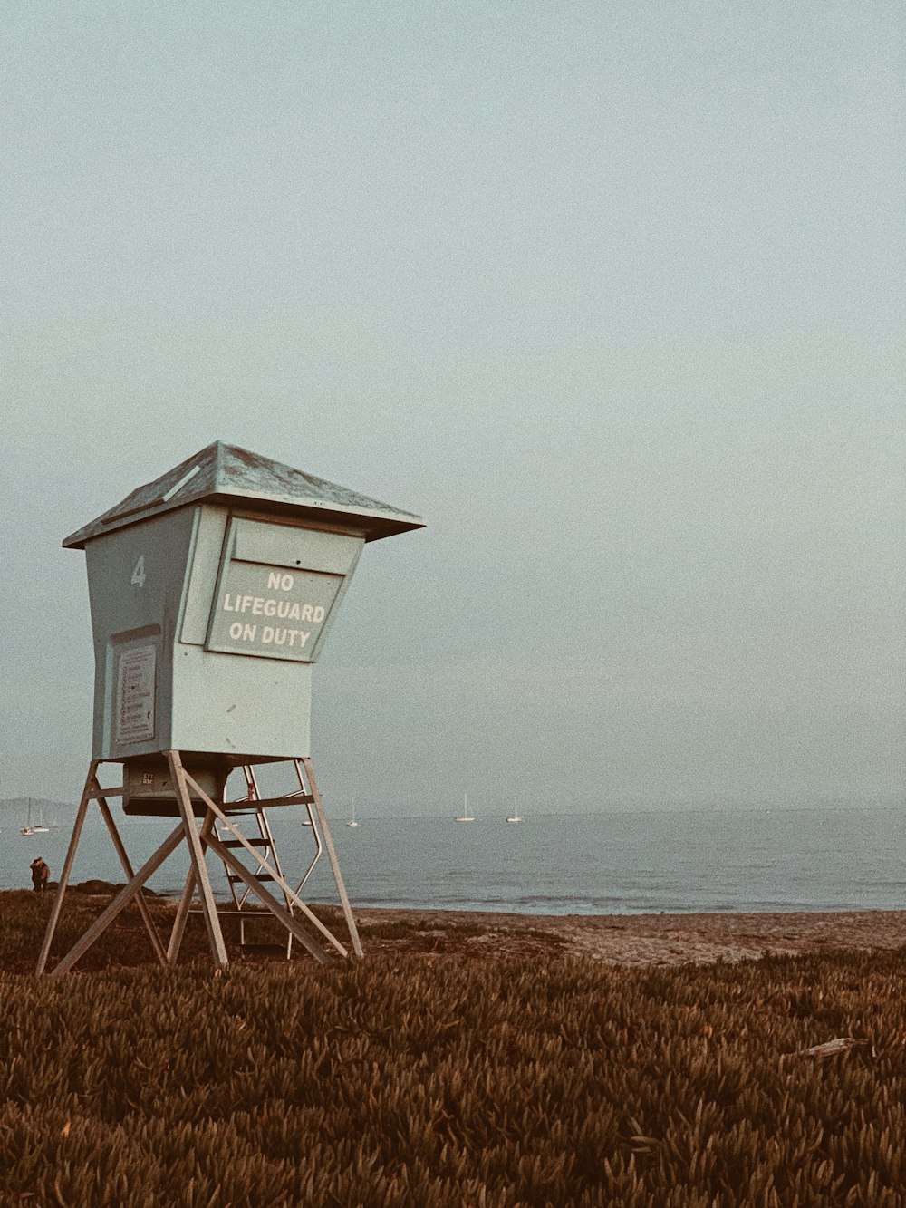 white wooden lifeguard house on brown field under white sky during daytime