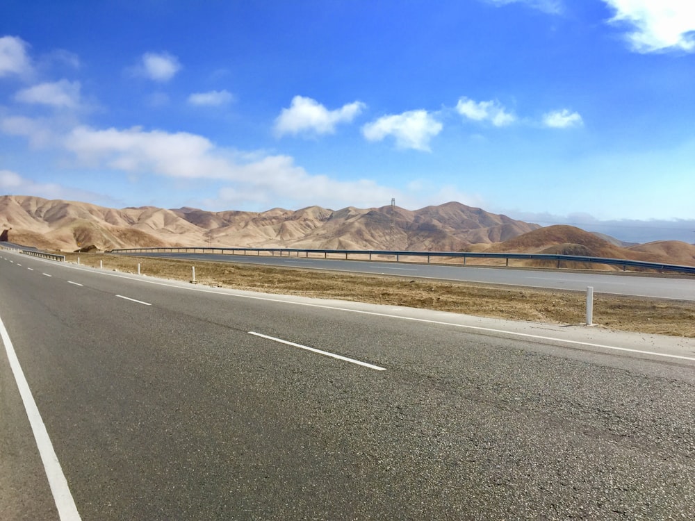 Carretera de hormigón gris cerca de Brown Mountain bajo el cielo azul durante el día