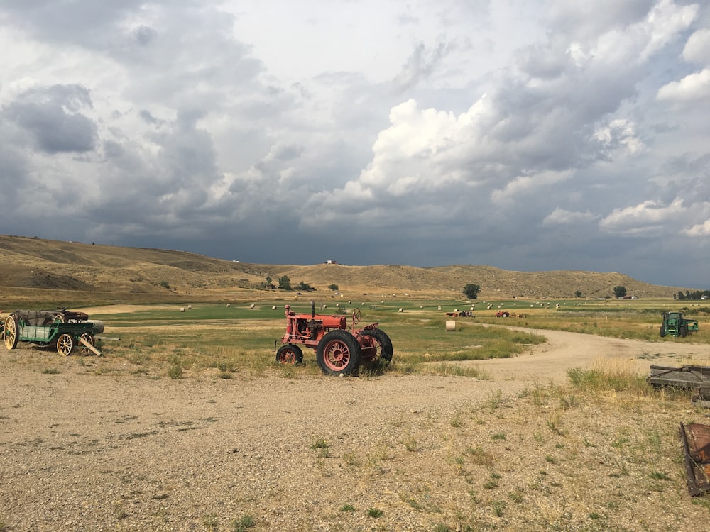 red tractor on brown field under white clouds during daytime