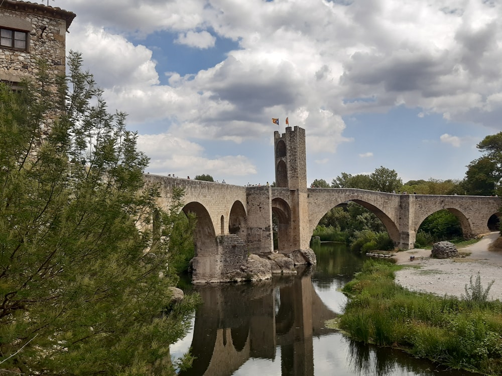 brown concrete bridge over river under blue sky and white clouds during daytime