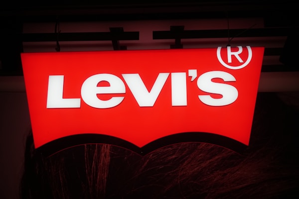 A bright red sign with the text 'Levi's' in bold white letters and a registered trademark symbol. The sign has a recognizable arch shape underneath the text.