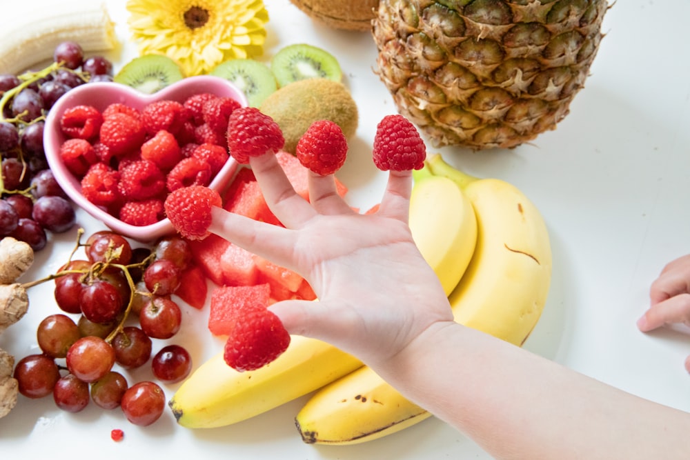 person holding a ripe banana and strawberries