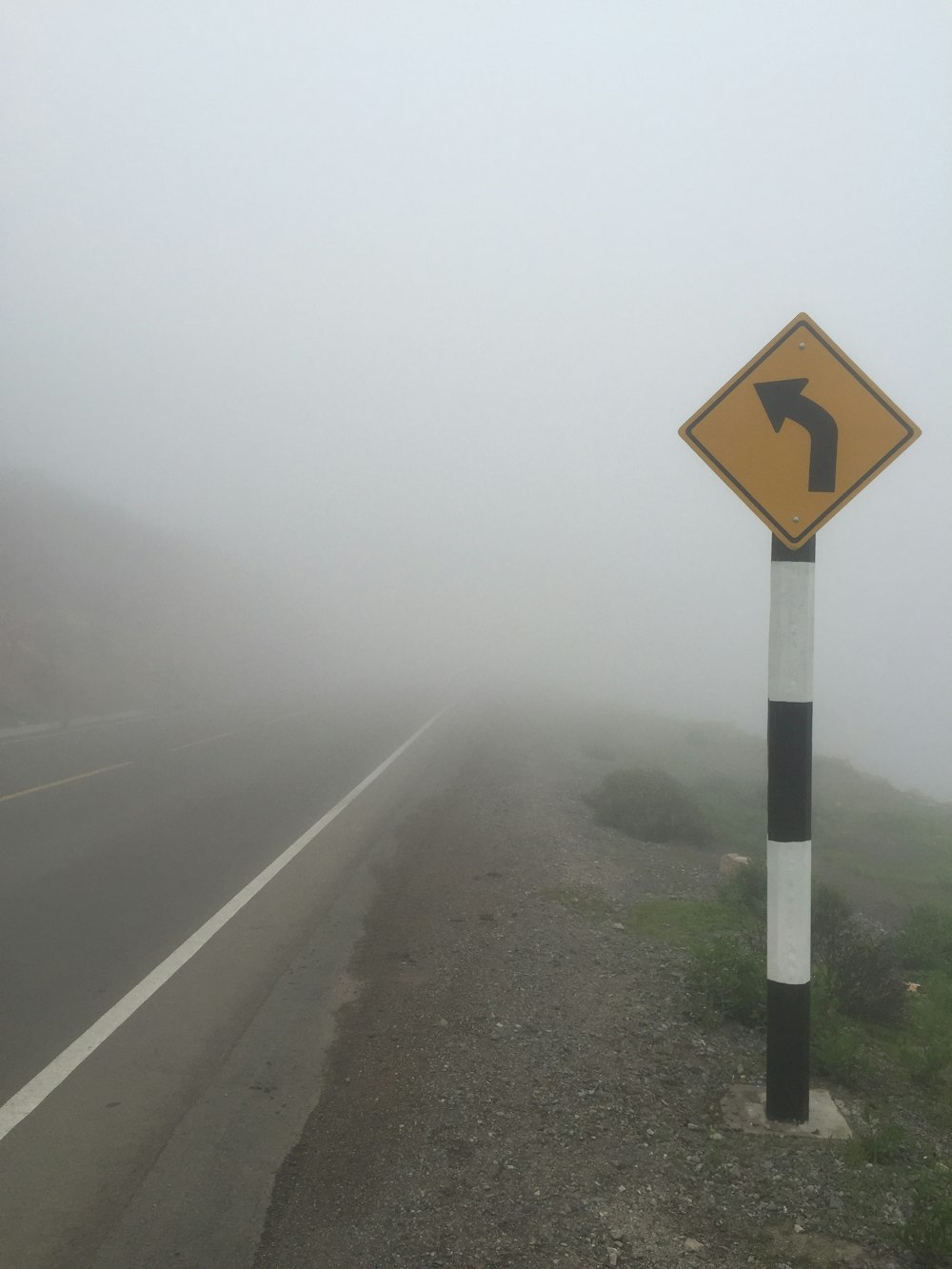 black and yellow road sign on foggy weather