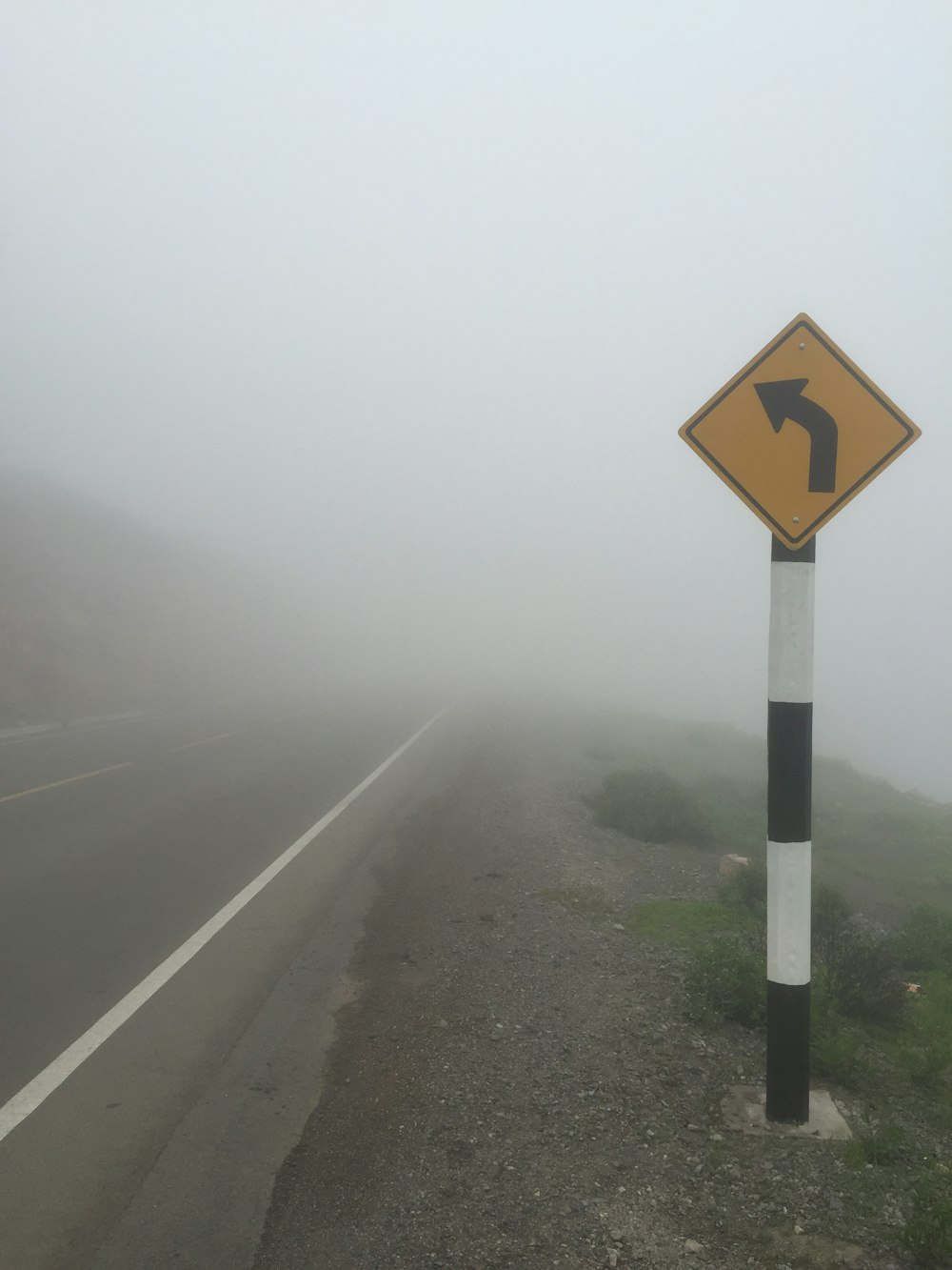 霧の天気に黒と黄色の道路標識