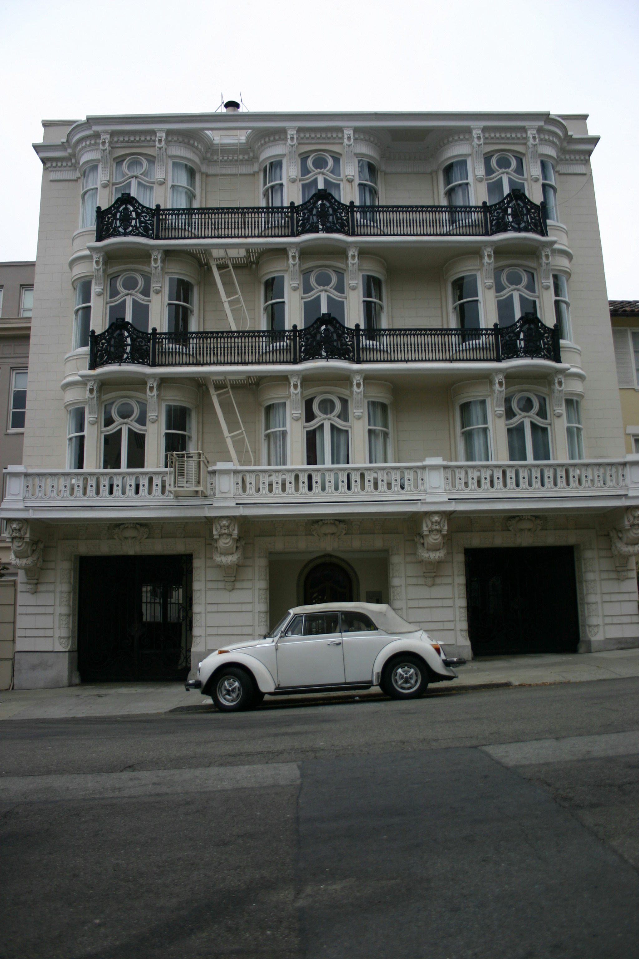 white sedan parked in front of white concrete building
