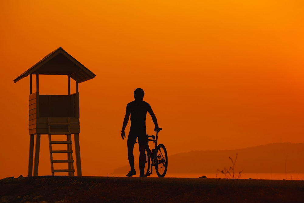 Ein Mann, der neben einem Fahrrad neben einem Rettungsschwimmerturm steht