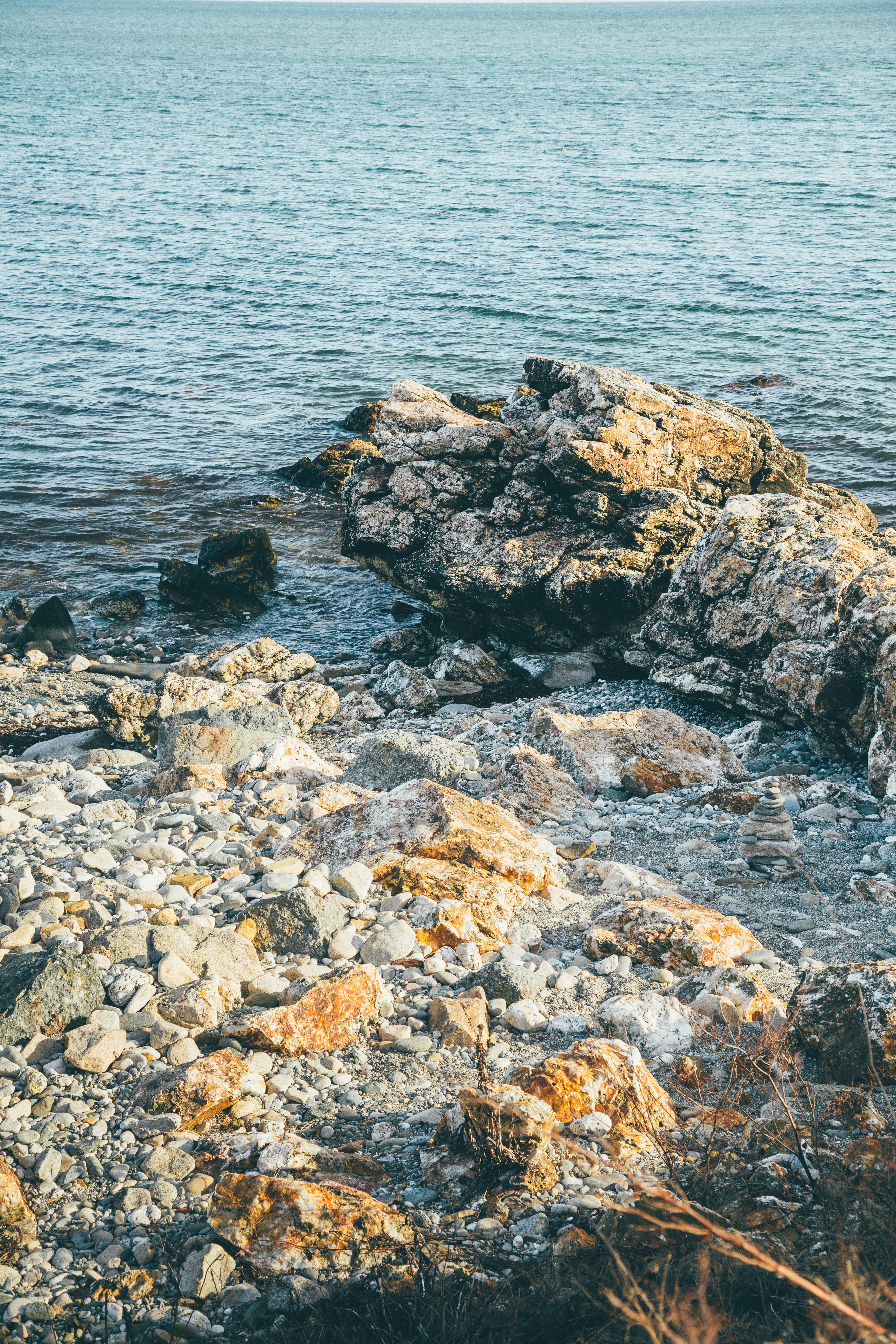 gray and brown rocks beside body of water during daytime