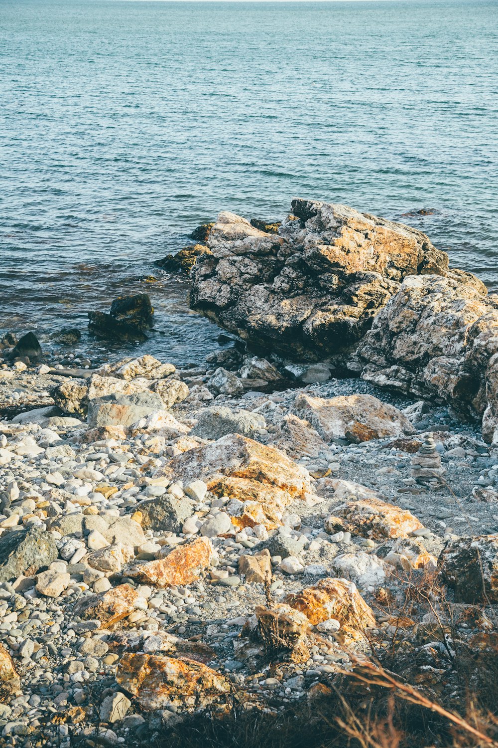 rochas cinzentas e castanhas ao lado do corpo de água durante o dia