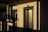 A building exterior with a sign reading 'Harbor Office' above a door. The building features green trim around windows and doors, and there is an elevator door next to the office door. The angle of the sunlight casts long shadows across the facade.