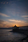silhouette of dock on sea during sunset