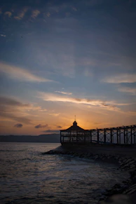 silhouette of dock on sea during sunset