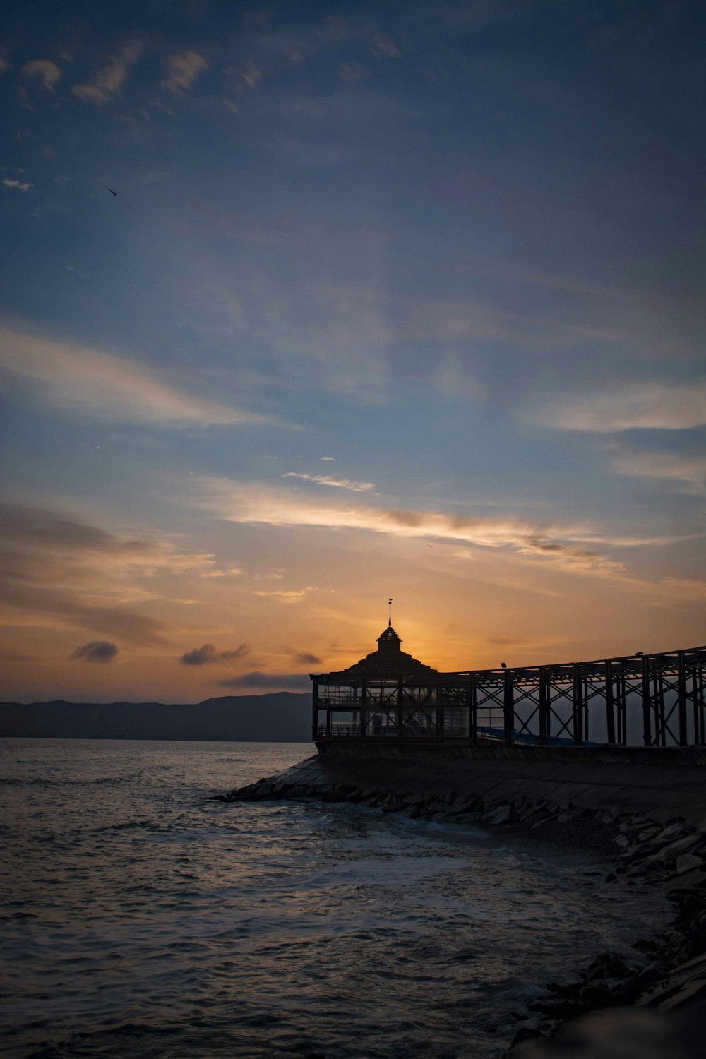 silhouette of dock on sea during sunset