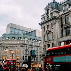 red bus in front of gray concrete building during daytime