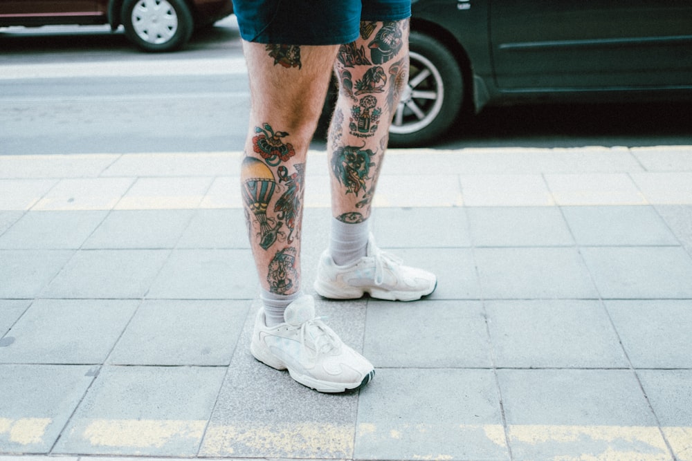 person in blue denim shorts and white nike sneakers standing on gray concrete floor