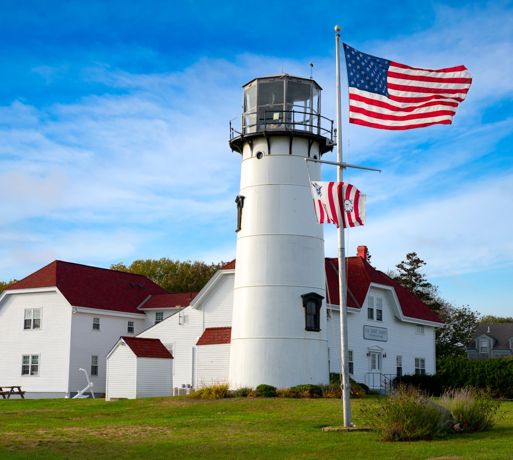 昼間の青空の下、白と赤の家の近くにある白と赤のコンクリート灯台