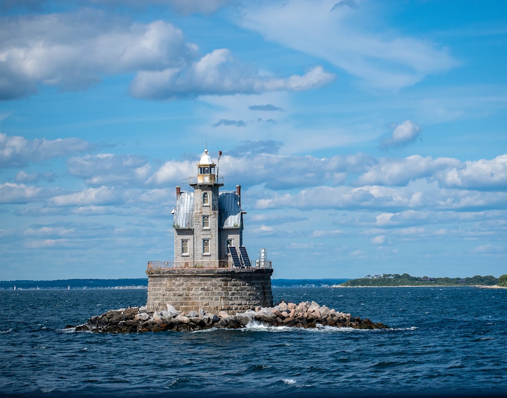 white concrete lighthouse near body of water under blue sky during daytime