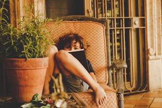 Kris C. Jefferson smiling warmly while holding a copy of Zoe’s Adventures with Elliot the Dragon in a cozy reading nook.