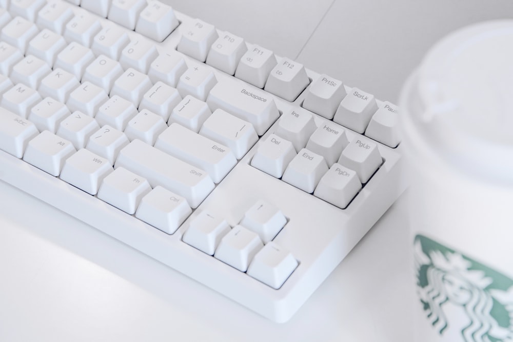 teclado de computadora blanco sobre mesa blanca