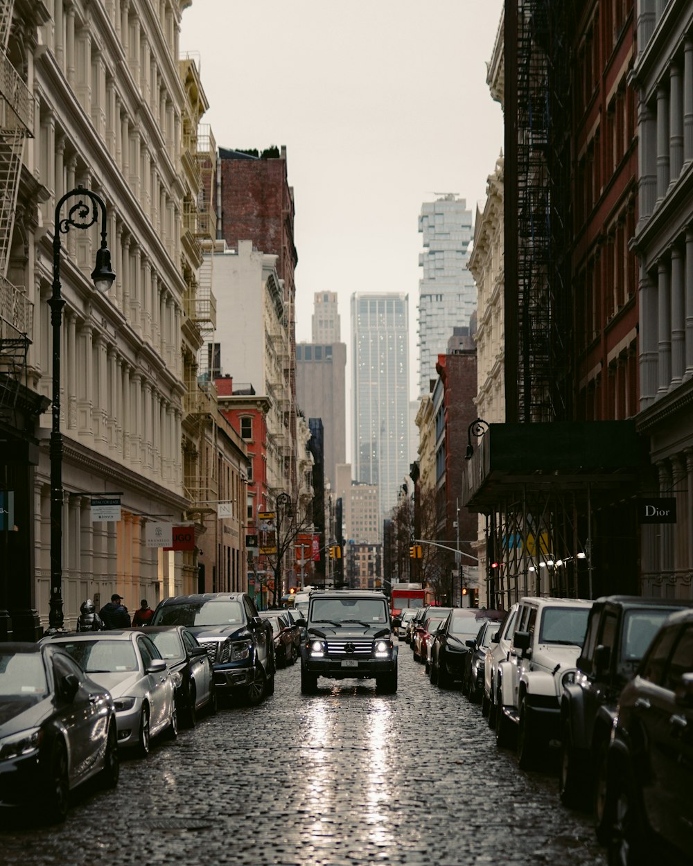 cars parked on street between high rise buildings during daytime