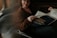 A person sits comfortably on a couch reading a newspaper. The newspaper features an advertisement for a career and graduate school fair. The lighting is soft and subdued, casting gentle shadows.