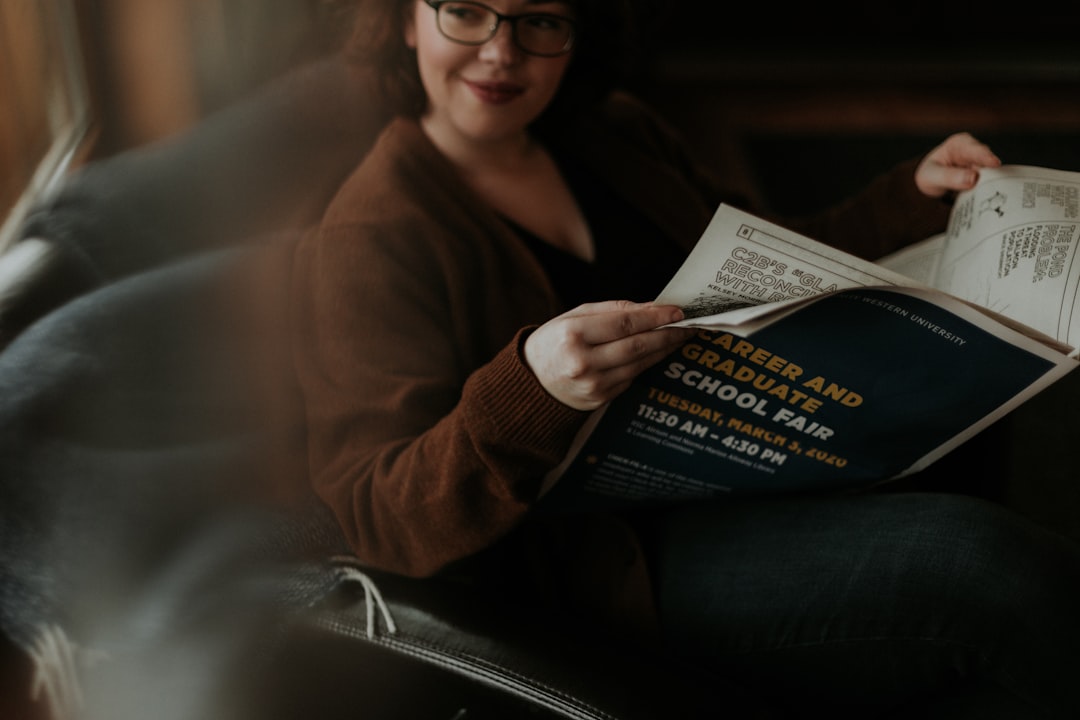 woman in brown long sleeve shirt and blue denim jeans sitting on brown leather sofa