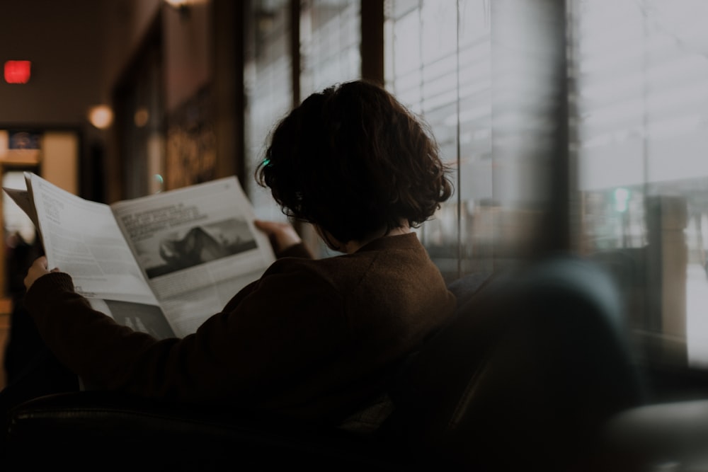 woman in brown long sleeve shirt sitting by the window