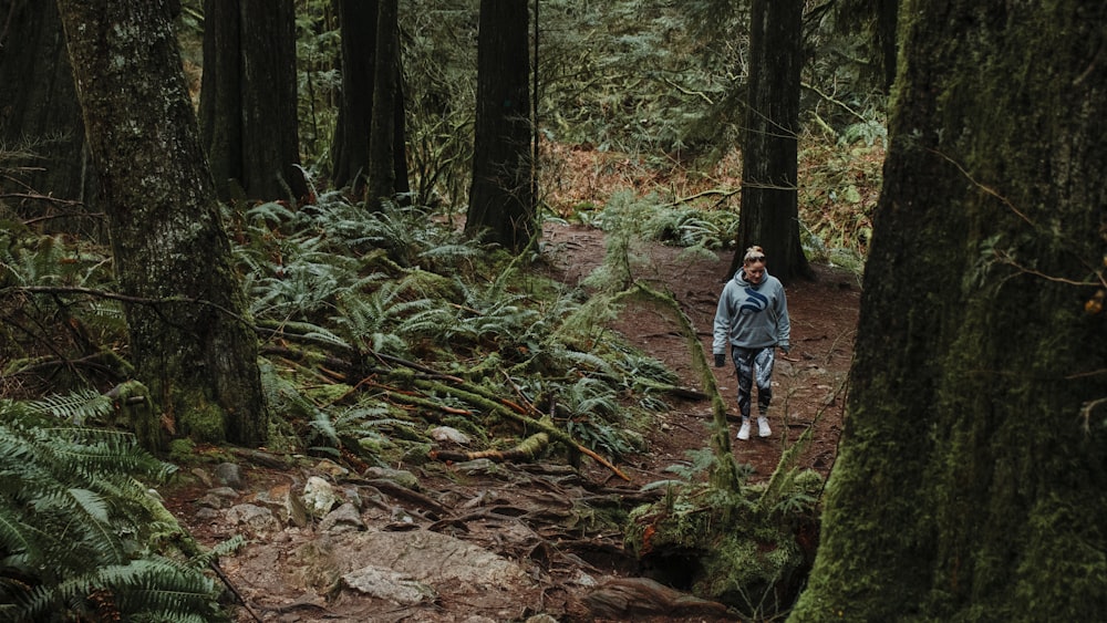 man in blue shirt walking on forest during daytime